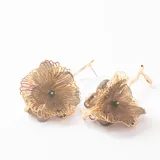 Caravanas colgantes con diseño de flor tridimensional, combinando pétalos de malla metálica dorada y tela semitransparente en tono marrón. Presentan un tallo largo y estilizado en metal dorado con cierre de perno.