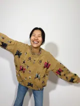 Sweater tejido color mostaza con cuello redondo y diseño bordado a mano con lana merino, con motivos de insectos de diversos colores.