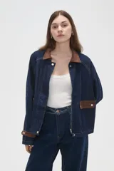 Campera de jean azul oscuro con cuello y puños de pana en color marrón. Presenta cierre frontal, costuras a la vista y detalles de botones metálicos en los puños.