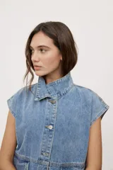 Chaleco de jean negro de calce relajado, con cuello camisero, cierre frontal con botones metálicos y bolsillos delanteros con solapa.