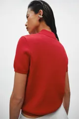 Top de punto de algodón color rojo, con cuello polo, manga corta y cierre frontal con cremallera blanca a contraste.