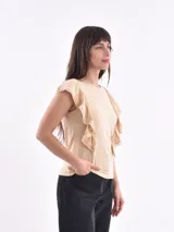 Remera de algodón color amarillo pastel, con cuello redondo y volados decorativos en los hombros con detalle de calado.