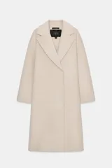 Abrigo de mezcla de lana color beige claro, de corte oversize y largo medio. Presenta un cuello solapa envolvente con detalle de pañuelo integrado y manga larga. Cierre frontal cruzado con botones ocultos.