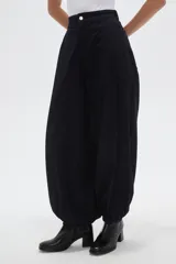 Pantalon de jean estilo barrel, color azul oscuro, con cintura de tiro medio, cierre frontal con botón metálico y puños elásticos en los tobillos.