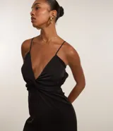 Mono negro de sastrería con breteles finos ajustables, escote en V con nudo y detalle trenzado en la espalda. Pantalón palazzo.