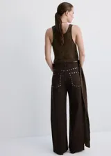 Jeans de corte recto y tiro medio color marrón, con detalles de tachas metálicas en las costuras laterales.