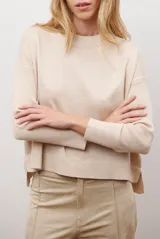 Buzo de punto color beige, con cuello redondo y manga larga.
