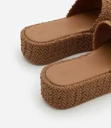 Sandalia tipo flatform con suela de plataforma plana y tira ancha superior, ambas con textura trenzada. Diseño sin cierre con puntera redonda.