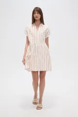 Vestido corto de corte holgado con diseño de rayas verticales en tonos claros. Presenta cuello camisero, cierre frontal con botones, mangas cortas y falda con volados escalonados.