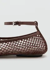 Zapato plano estilo Mary Jane color marrón, confeccionado con tejido de malla tipo red con diseño de rejilla. Cuenta con punta redondeada, suela plana y tira ajustable con hebilla metálica en el tobillo.