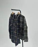 Camisa de manga larga con diseño de cuadros escoceses en tonos verde oliva, blanco y negro. Presenta cuello clásico, cierre frontal con botones y corte holgado.