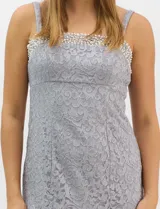 Vestido largo de encaje color beige, con escote recto decorado con pedrería y perlas, tirantes anchos y tajo lateral en la falda.