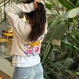 Buzo de cuello redondo color crudo, con diseño estampado en la espalda que presenta una estrella de mar estilizada sobre un fondo de formas geométricas abstractas en tonos azul, amarillo y rosa.