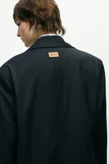 Blazer sastrero negro de corte oversize con solapas de muesca y cierre frontal con dos botones.