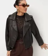 Campera estilo biker de cuero sintético color negro, con cuello solapa, cierre frontal asimétrico, bolsillos laterales con cremallera y detalles de botones metálicos en hombros y solapas.