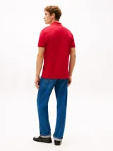 Chomba Tommy Hilfiger de corte regular, color rojo, confeccionada en piqué de mezcla de algodón elástico con tecnología Flex. Cuenta con cuello polo, cierre frontal de dos botones y el logo distintivo de la marca bordado en el pecho.