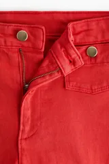 Jean rojo de tiro alto, corte wide leg y diseño tobillero, con bolsillos delanteros tipo parche con botón y pliegues marcados.