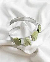 Brazalete rígido plateado con tres piedras serpentina color verde claro.