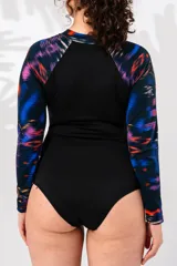 Malla entera de lycra con estampado abstracto en tonos azules, naranjas y violetas. Tiene cierre frontal con cremallera y mangas largas.