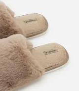 Pantufla cerrada de mujer confeccionada en tejido de peluche suave, con suela de goma termoplástica.