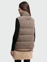Chaleco acolchado de lana con diseño a cuadros en tonos marrón, beige y negro. Presenta cuello alto, cierre frontal con cremallera y el parche del logo de Moncler en el pecho.