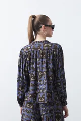 Blusa de manga larga con cuello en V y estampado abstracto en tonos azul y marrón oscuro.
