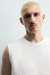 Camiseta sin mangas de corte relajado, con cuello redondo y diseño liso en color blanco.