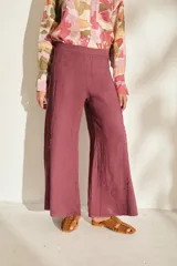 Pantalón ancho de lino color bordó, de tiro alto con cintura elástica y costuras laterales desflecadas.