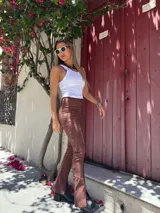 Pantalón marrón acampanado de gabardina elastizada con ojalillos metálicos en los laterales.