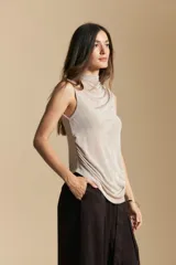 Top sin mangas de color negro con cuello alto y diseño drapeado en el frente. Confeccionado en una tela suave con acabado levemente satinado y silueta fluida.