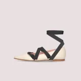 Ballerinas color crema de piel, con punta fina y lazo negro que se ata al tobillo.