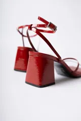 Sandalias de tacón cuadrado medio, color negro con acabado brillante, diseño de tiras finas en el empeine y cierre de pulsera con hebilla al tobillo.
