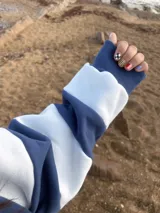 Buzo de tela deportiva con felpa color crudo y azul, con cuello y bordado anaranjado.