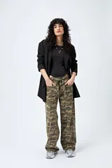 Pantalón de tiro bajo con estampado camuflado, confeccionado en tela liviana de calce amplio. Su diseño incorpora cintura regulable con cordón y bolsillos utilitarios.