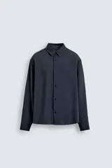 Camisa de corte relajado, color azul marino, con cuello solapa, manga larga con puños abotonados y cierre frontal de botones.