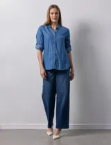 Camisa gris de tencel con cuello con solapa, escote en V y abertura central con botones. Largo de manga regulable con presilla y botón. Ruedo en espalda con tajo.