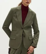 Blazer de sastrería color verde oliva, con corte oversized, solapas clásicas, cierre frontal de un botón y bolsillos con tapa. Cuenta con forro interno y textura sutil.