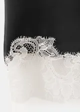 Falda corta de satén negro con detalle de delicada puntilla blanca en el borde inferior.