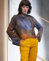 Buzo de lana merino afieltrada color gris con teñido artesanal tie dye en forma de luna. Cuello alto cruzado y aberturas laterales.