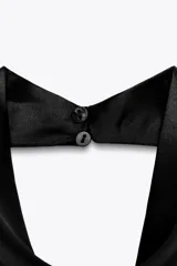 Top blanco satinado con cuello halter y escote fluido. Cierre en la espalda con botones.