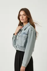 Campera de jean celeste de manga larga, con cuello camisero, botones frontales y bolsillos de parche con solapa en el pecho.