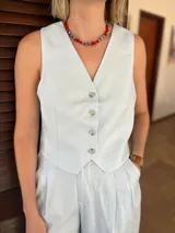 Chaleco sastrero sin mangas, color celeste claro, con escote en V y cierre frontal de tres botones.