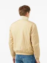Campera de nailon color beige con cierre frontal de cremallera, cuello alto de canalé, puños y bajo elásticos. Presenta el logo de Calvin Klein bordado en el pecho y un parche con el logo en la manga izquierda.