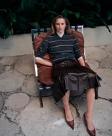 Falda midi plisada de cuero sintético en color marrón oscuro, con diseño de talle alto y caída acampanada.