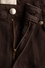 Pantalón bootcut de sarga de algodón, color marrón, con cintura clásica, cierre con botón y bolsillos delanteros. Presenta pliegues marcados al frente y en la parte trasera.