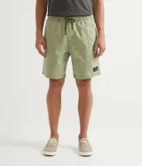 Bermuda masculina de sarga color verde oliva, con cintura elástica y cordón de ajuste. Cuenta con bolsillos laterales y traseros, y una pequeña etiqueta decorativa aplicada en el ruedo.