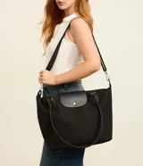 Cartera grande Satinato de color negro, confeccionada en poliéster con detalles en poliuretano. Cuenta con compartimento principal con cierre de cremallera, solapa frontal con broche a presión y doble asa de hombro.
