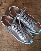 Zapatilla urbana de cuero con diseño combinado en color dorado metalizado y gamuza en tono tostado. Presenta cordones al tono, suela de goma blanca y detalles en cuero marrón en la parte posterior.