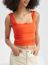 Top corto de color rojo con escote cuadrado, tirantes anchos y un pequeño lazo decorativo en el centro del pecho.