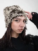 Gorro tipo beanie con diseño de tejido desmechado en tonos marrón y crudo.